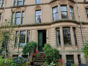 Elegant stone building with curved windows and greenery.