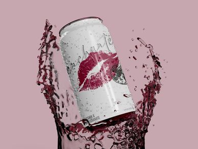 A can with a lipstick kiss design splashing into pink liquid.