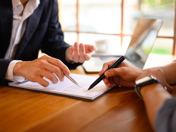 Closeup lawyer or insurance agent pointing at contract showing male client where to signature sign