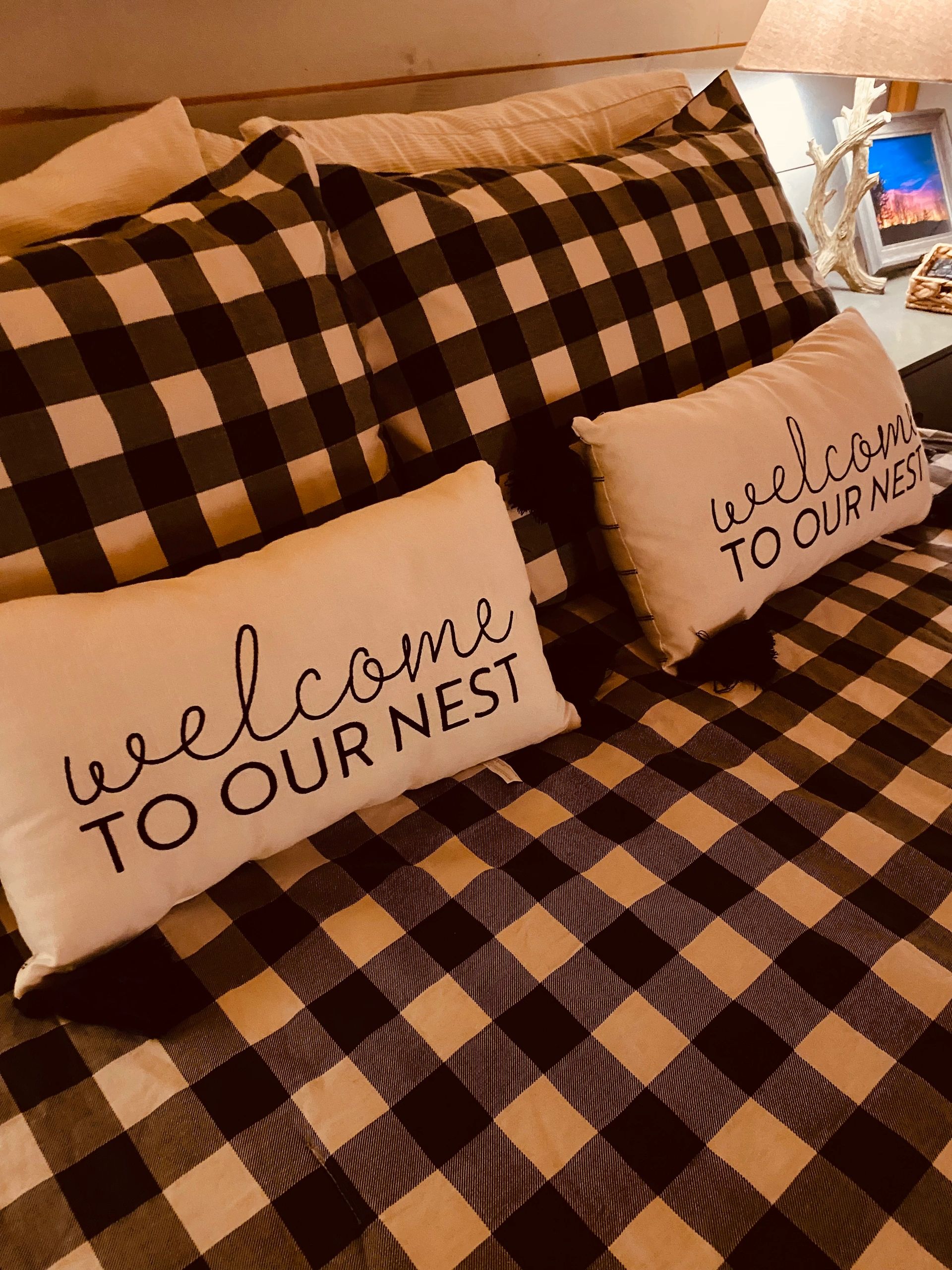 Cozy bed with checkered pillows and a welcoming message.