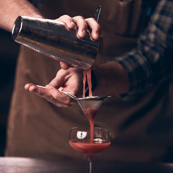 fine straining a drink into a coupe glass