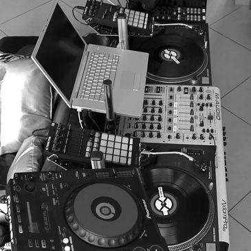 DJ setup with turntables, mixer, laptop, and controllers.