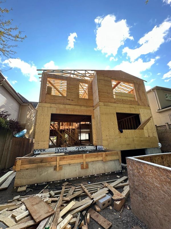 A wooden house frame under construction on a sunny day.