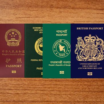 Four different passports from various countries lying on a wooden surface.