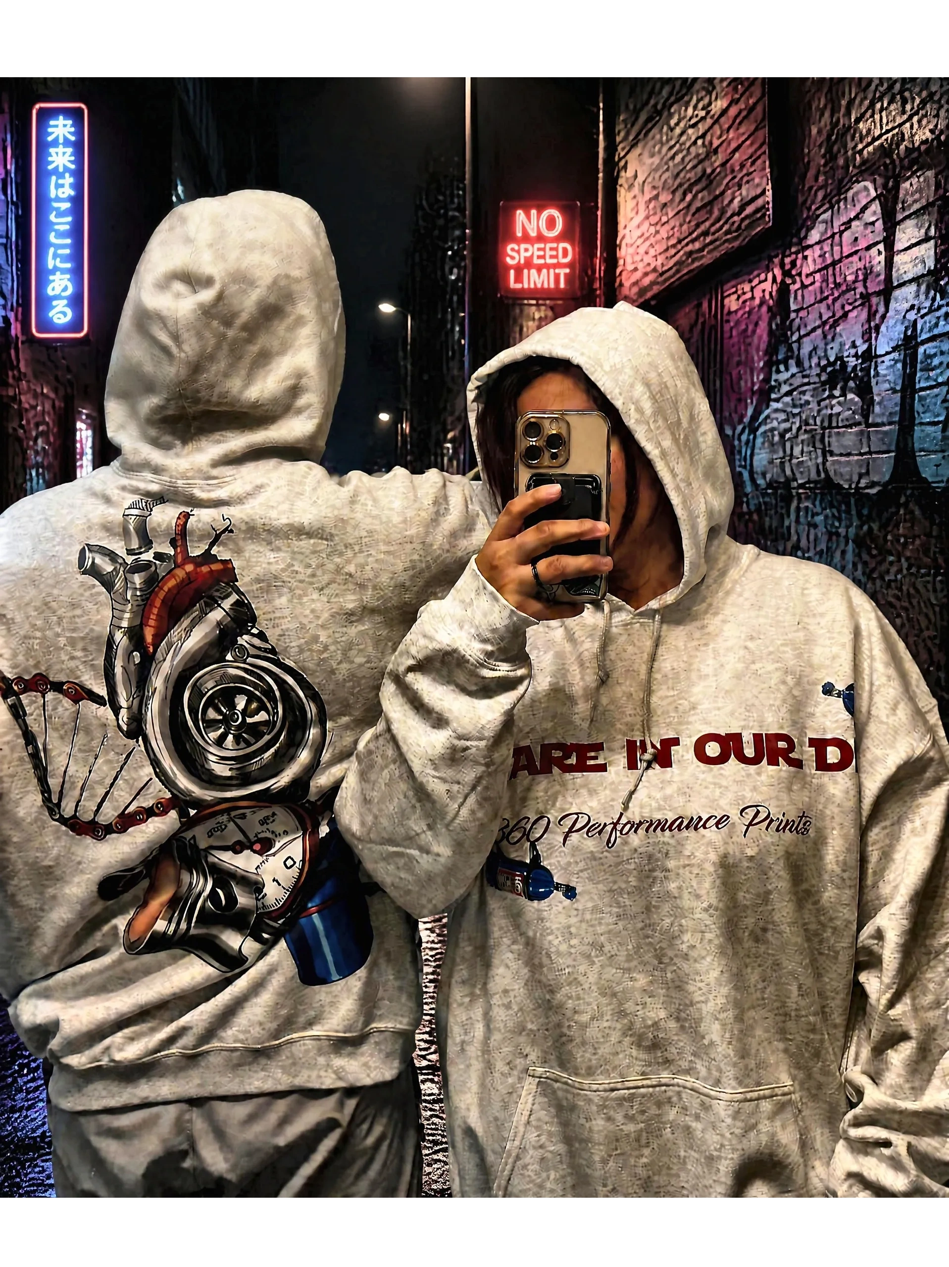 Two people wearing 360 Performance Prints custom hoodies in a neon-lit street