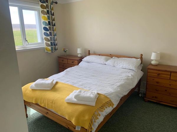 Cozy bedroom with wooden furniture, white bedding, and a yellow throw blanket.