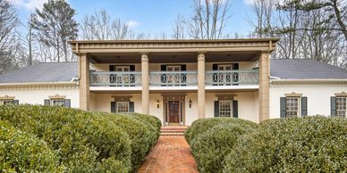 Large two-story house with columns and a brick pathway.