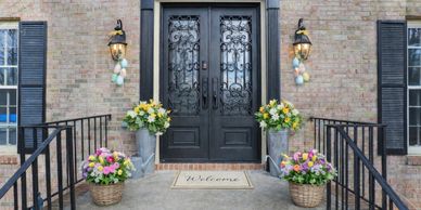Front porch with black double doors, colorful flower arrangements, and Easter egg decorations.