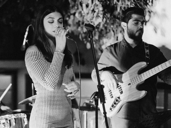 A woman singing with a man playing bass guitar in a live band.