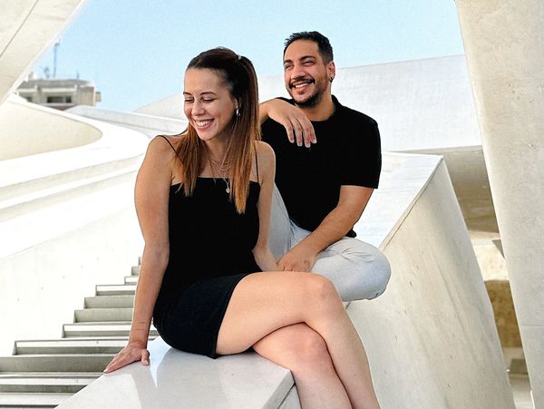 A smiling couple sitting on modern white architecture steps.