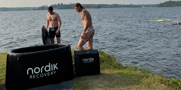 Two men preparing a nordik recovery cold plunge by a lake.