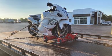 White sports motorcycle secured on a trailer at sunset.