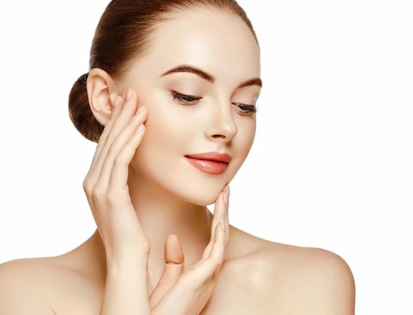 Young woman with flawless skin gently touching her face, showcasing natural beauty.