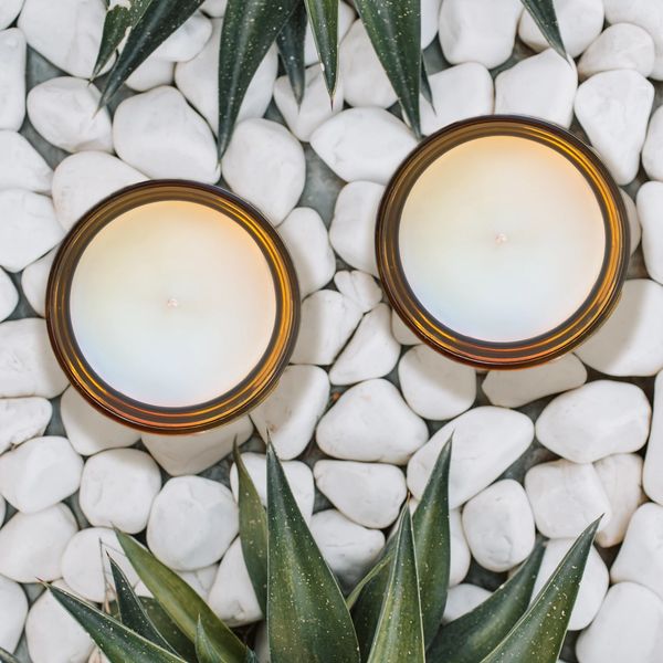 Two candles on white stones with green leaves.
