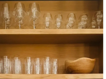 Wooden shelves with glasses and a wooden bowl.