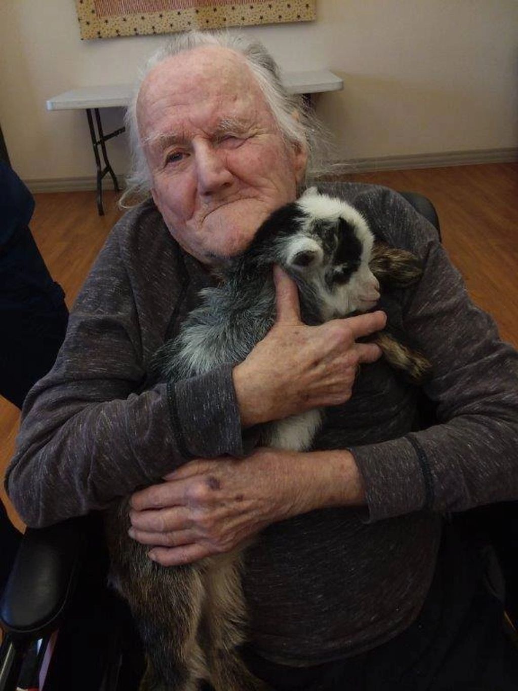 Nursing home resident cuddling & holding one of our bottle baby goats during animal therapy in 2019.