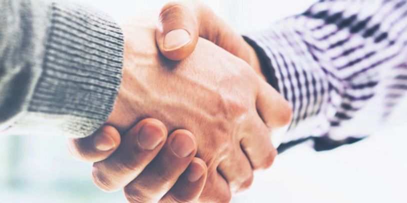 Two people shaking hands in a professional setting.