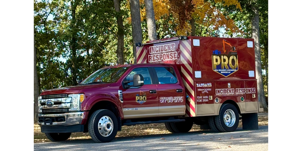 A maroon incident response truck parked outdoors with fall foliage in the background.