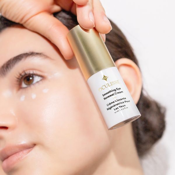 Close-up of a woman applying Oculisse Smoothing Eye Renewal Cream near her eye.