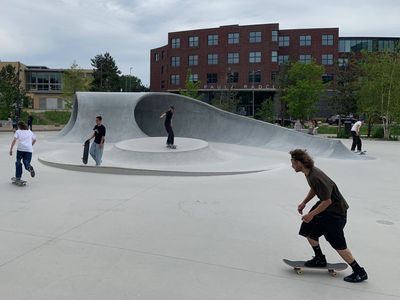 Skateboarders at an urban skate park with modern architecture.