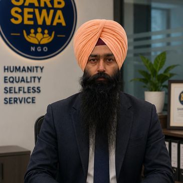 Man in a peach turban and suit sits confidently at a desk in an NGO office.