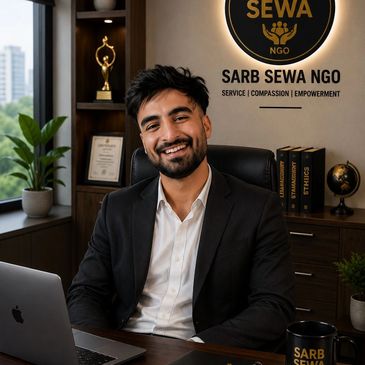 Smiling man in office with Sarb Sewa NGO logo behind him.
