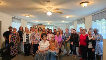 A large group of women gathered indoors smiling for a photo.