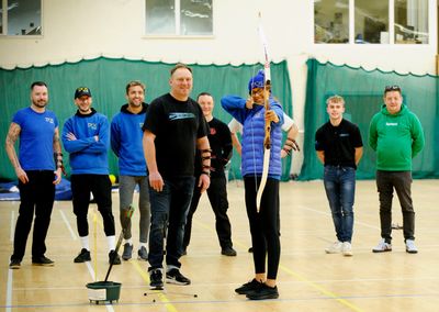 Group of people taking part in an indoor archery teambuilding event