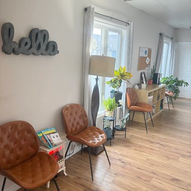 Cozy waiting area with brown chairs, plants, and a warm lamp.