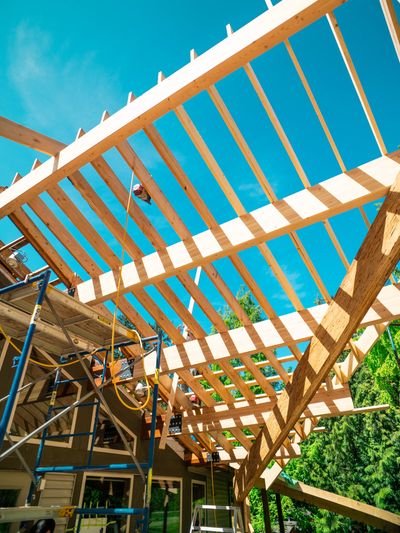 Wooden pergola under construction with blue sky.