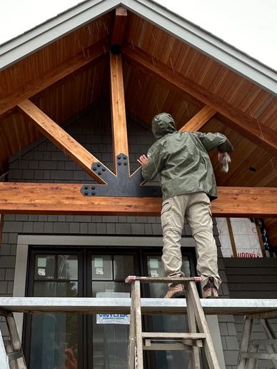 Man working on wooden beams on a ladder.