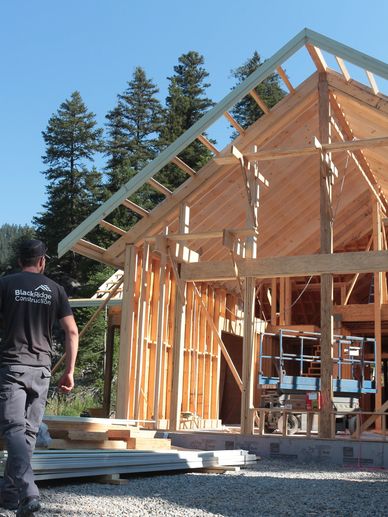 Construction of a wooden house frame in progress.