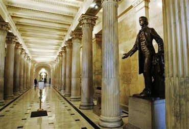 Statue in a grand hallway lined with tall columns and marble floors.