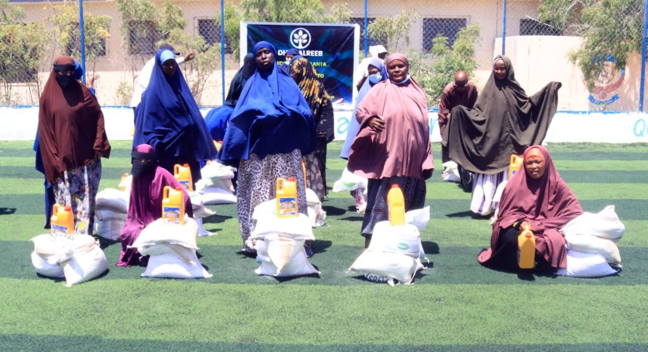 Women receiving aid packages with food supplies outdoors.