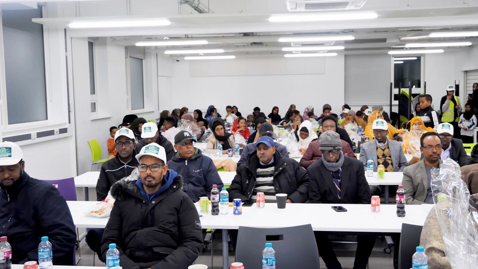 A diverse group of people attending a community meeting in a brightly lit room.