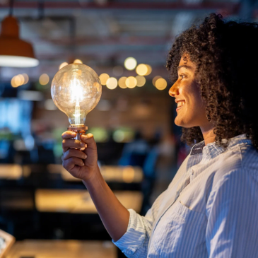 Woman holding a glowing light bulb.
