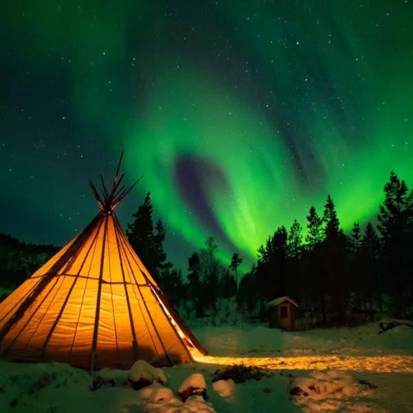 A spectacular display of Northern Lights, illuminates the night sky above a teepee