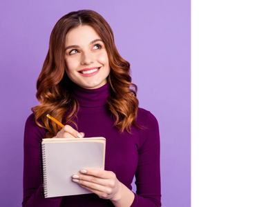 A pretty, grinning young woman in long auburn hair looking up, with a pencil and pad in her hands
