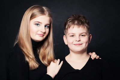 A pretty teenage girl with long blonde hair, affectionately next to a smiling boy with dimples