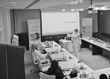 A formal meeting or workshop with a presentation in Arabic.