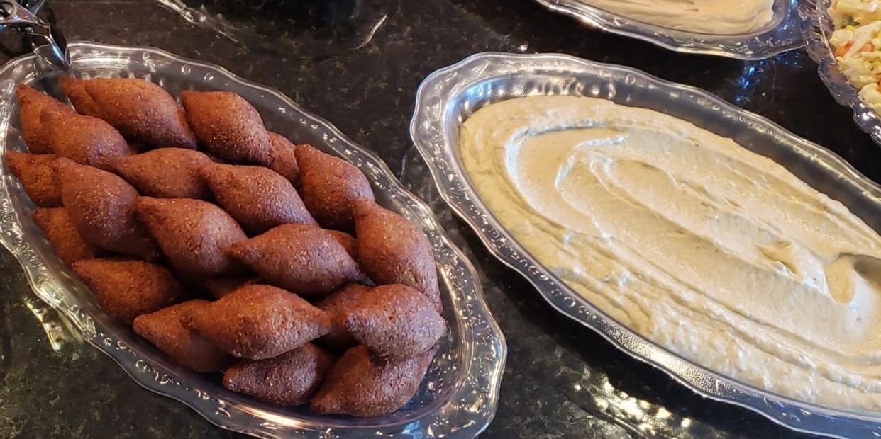 Plate of kibbeh and creamy hummus on a dining table.