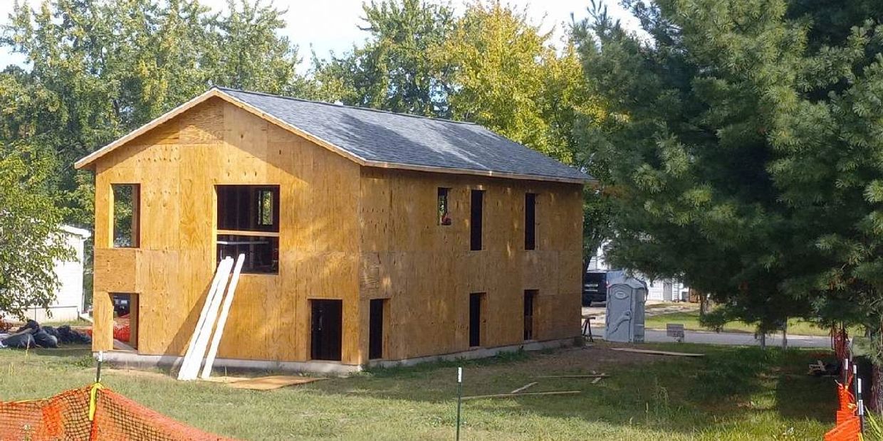 Two-story house under construction with wooden framing.