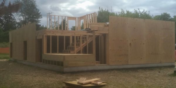 Partially built wooden house structure on a cloudy day.