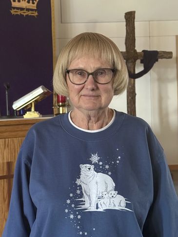 Older woman wearing glasses and a blue polar bear sweatshirt.