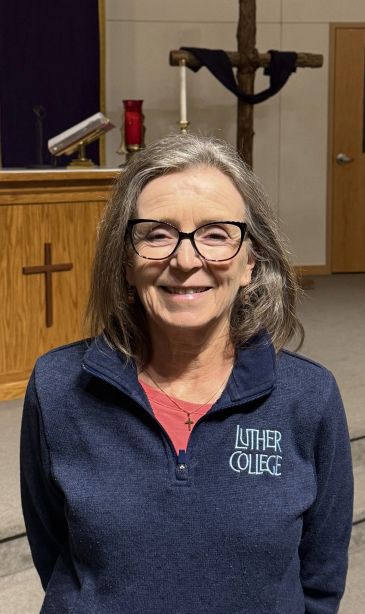 Smiling woman in a church wearing Luther College sweatshirt.