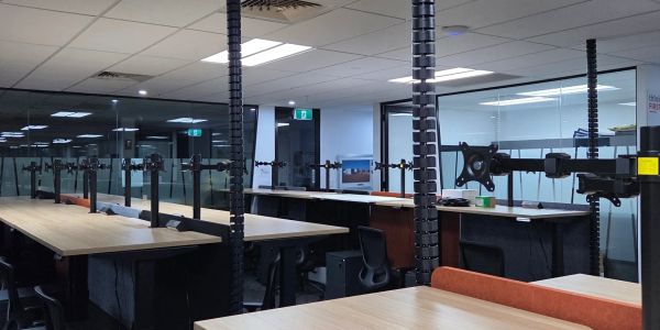 Empty modern office space with multiple desks and monitor mounts.