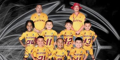 Youth football team posing in yellow uniforms with coaches behind them.
