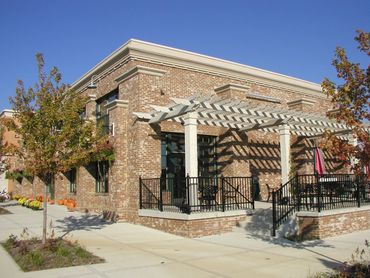 Brick building with a patio and pergola on a sunny day.