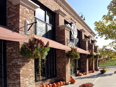 Brick building with pumpkins and hanging plants outside.