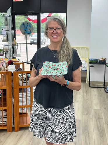 Woman holding a decorative ceramic dish in a shop.
